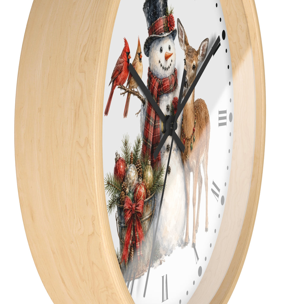 Round wall clock with a light natural wood frame and a white face featuring a festive winter scene with a snowman, deer, cardinals, pine branches, and ornaments.
