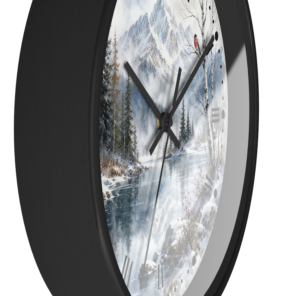 A round wall clock with a black frame and a printed winter landscape dial showing snow-covered mountains, trees, and a frozen river. The clock is shown at an angle against a plain white background.