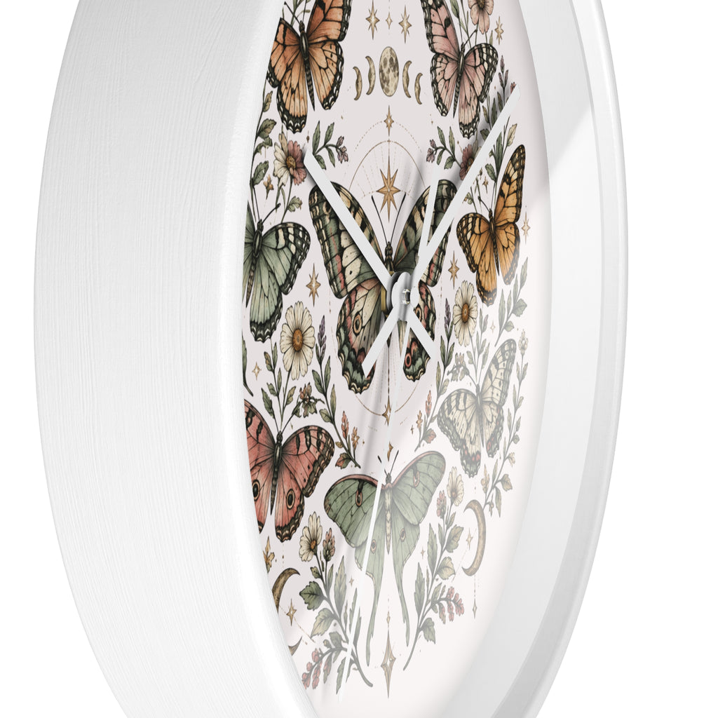 A white oval wall clock featuring a vintage-style printed dial with illustrated butterflies, flowers, and celestial symbols on a clean white background.