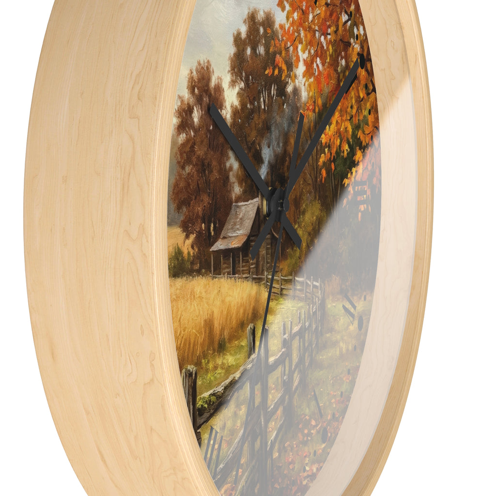 Round wall clock with a light natural wood frame and a scenic autumn landscape print featuring orange trees, a small cabin, and a fence, shown against a white background.