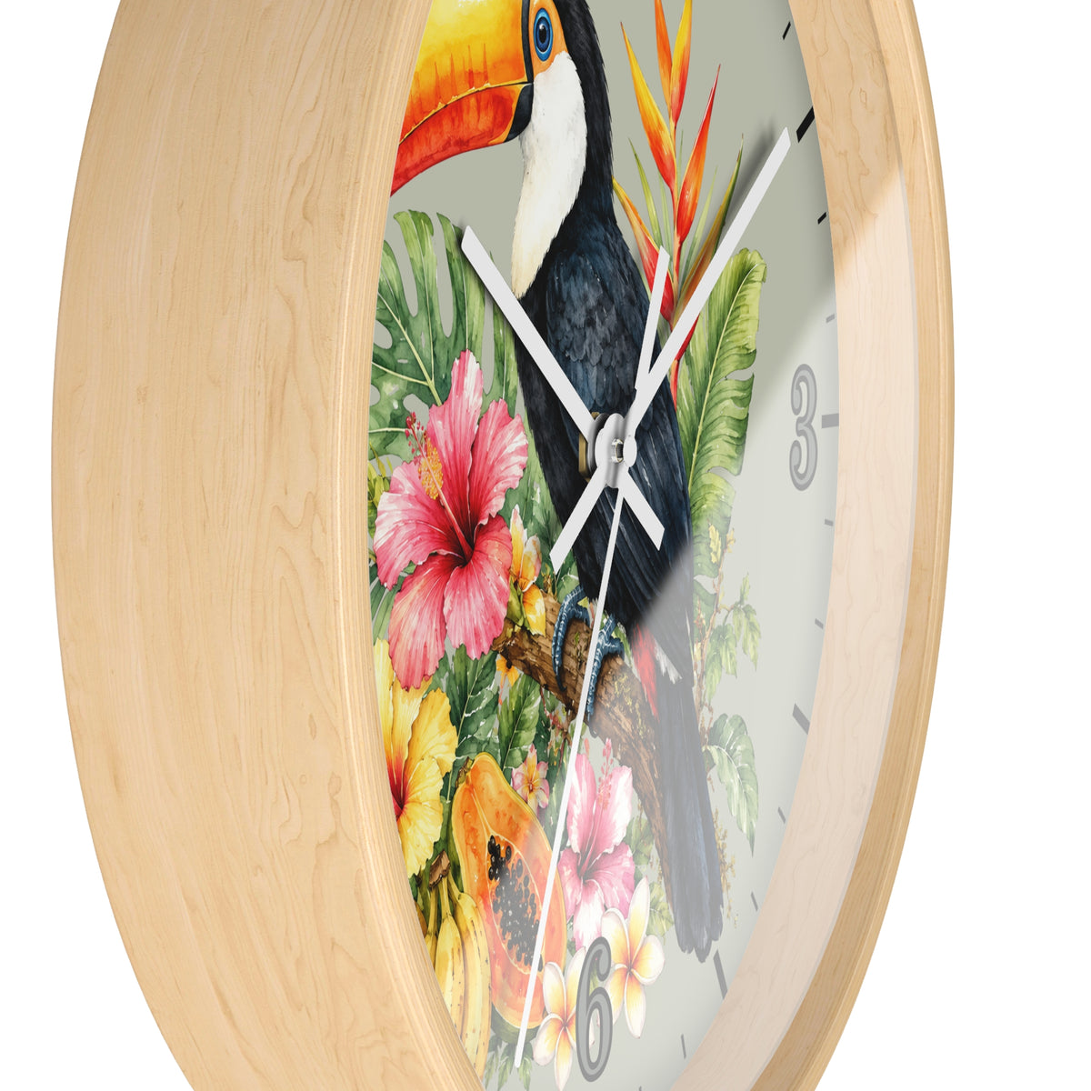 A round wall clock with a light natural wood frame and a tropical bird illustration on the face. The design features a toucan perched among colorful flowers and green leaves, with white clock hands and black numerals, shown against a plain white background.