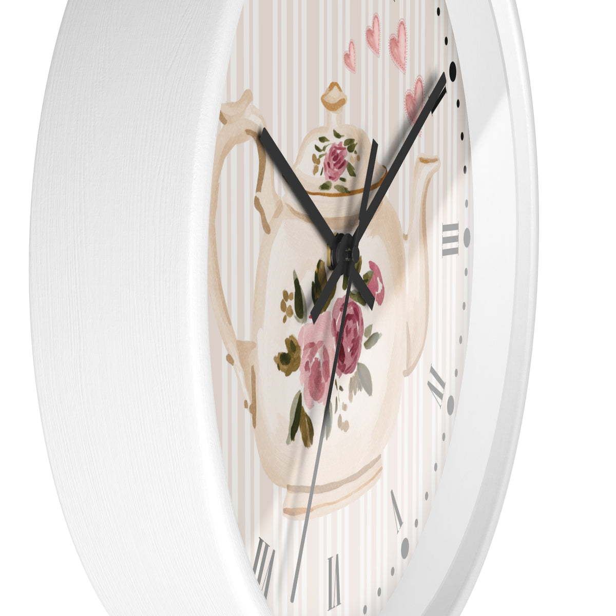 A close-up of a round wall clock with a white frame and a decorative dial featuring a cream teapot with pink roses, green leaves, and a striped background.