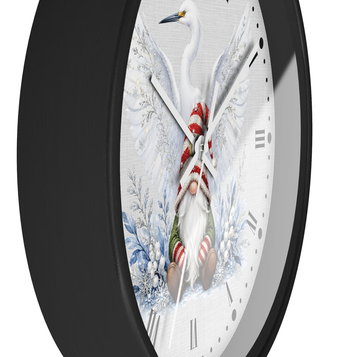 A close-up of a wall clock with a black frame and a white dial featuring a whimsical winter illustration: a white bird at the top, a small gnome wrapped in a red-and-white striped scarf and green pants near the bottom, and blue floral motifs around the dial.
