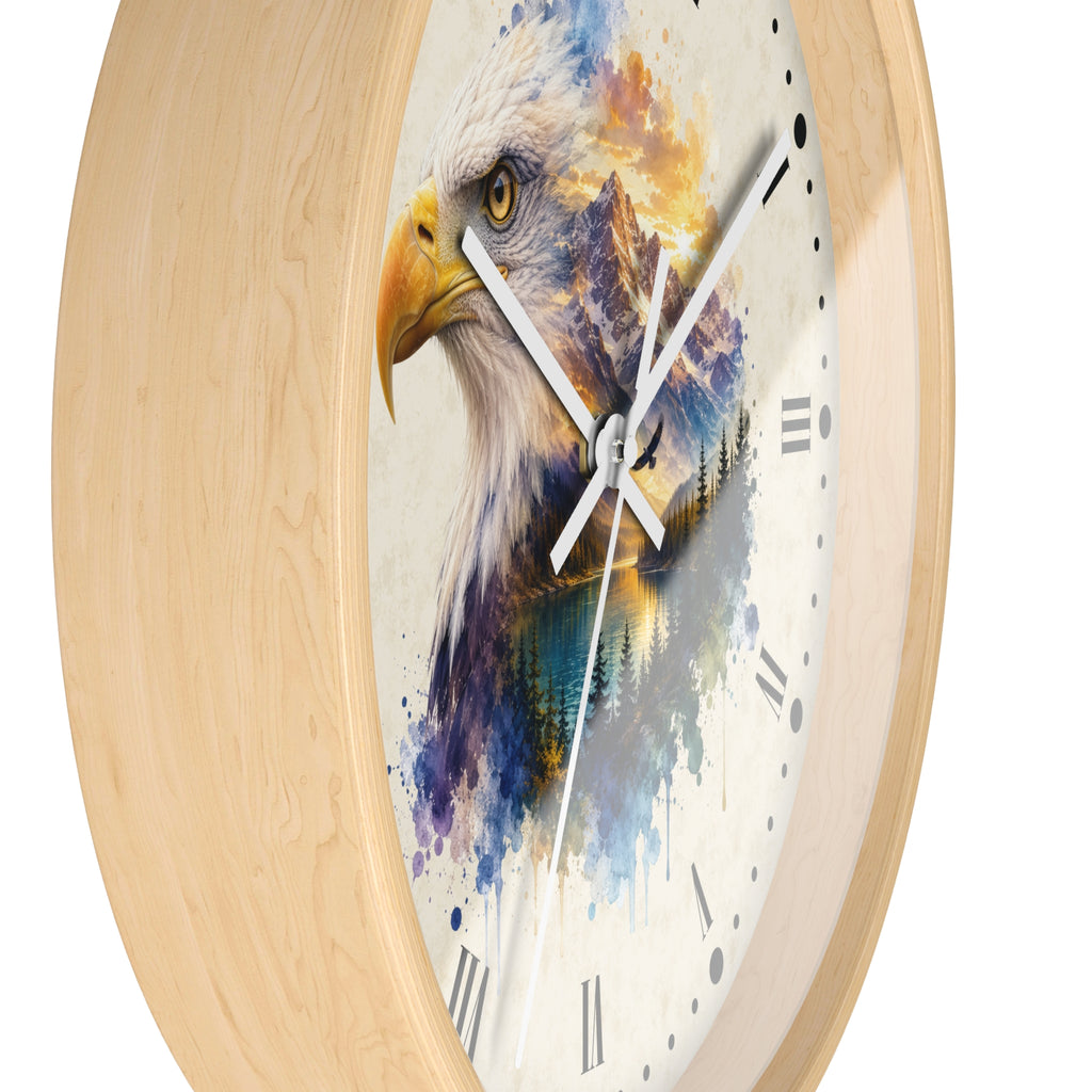 A round wall clock with a light natural wood frame and a printed design of an eagle's head in watercolor over a mountain landscape. The clock face is off-white with Roman numerals and white hands.