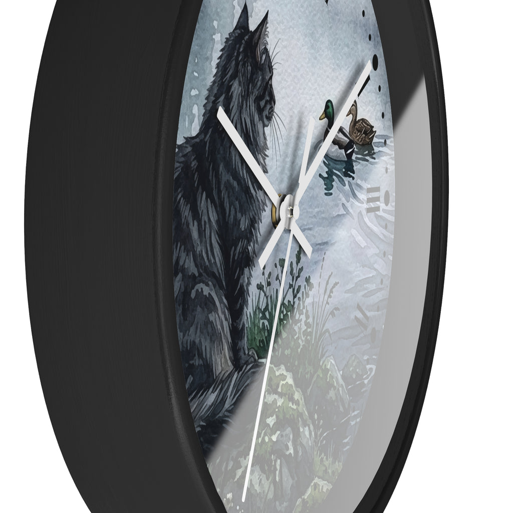 Round wall clock with a black frame and a printed illustration of a black cat beside ducks on a snowy water scene, shown against a white background.