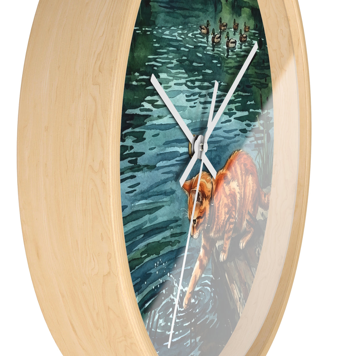 Oval wall clock with a light natural wood frame and a printed watercolor-style scene on the face showing a orange tabby cat in blue-green water with ducks overhead, against a plain white background.