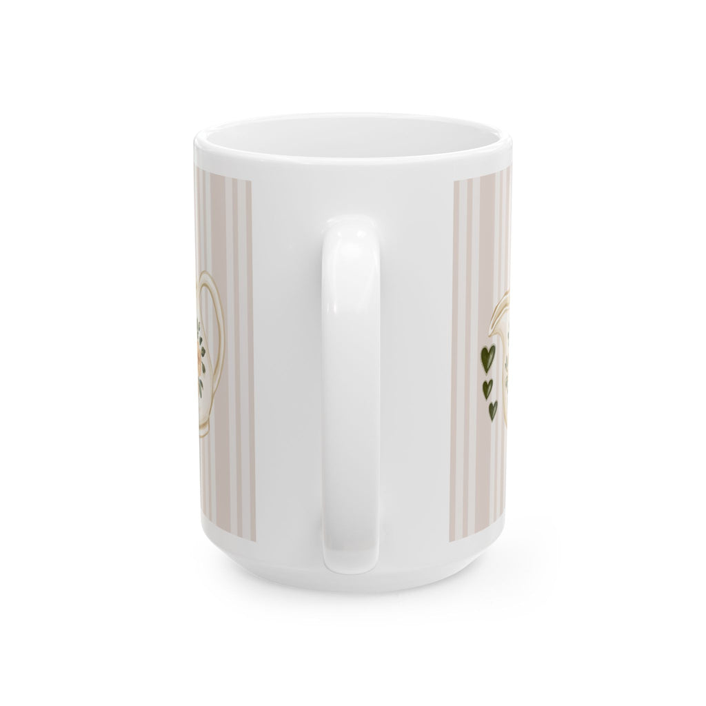 A white ceramic mug with a handle, decorated with vertical beige stripes and small gold and green heart details, shown against a plain white background.