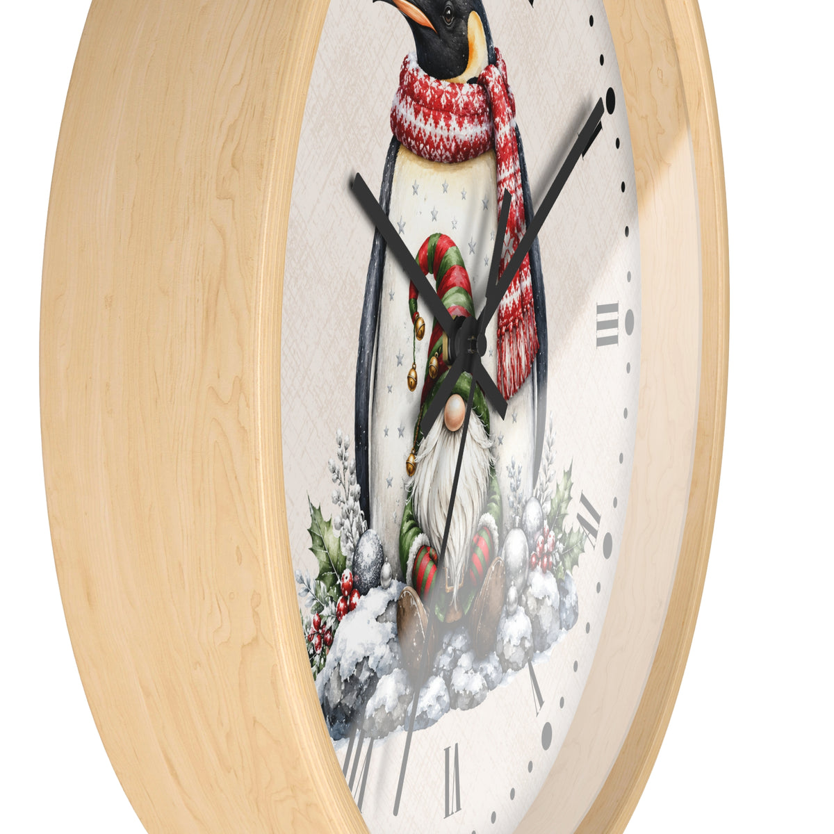 A close-up of a round wall clock with a light natural wood frame and a festive winter illustration on the dial. The design features a penguin wearing a red and white patterned scarf, standing next to a small Christmas gnome in a snowy setting with holly and berries.