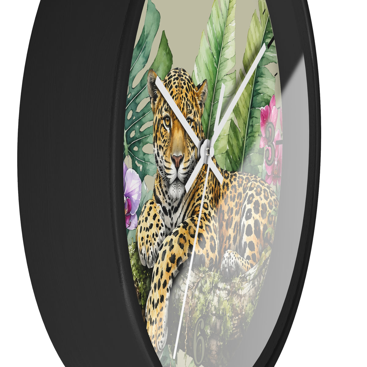 Round wall clock with a black frame and a printed tropical jungle design featuring a leopard, large green leaves, and pink flowers on a light beige background.