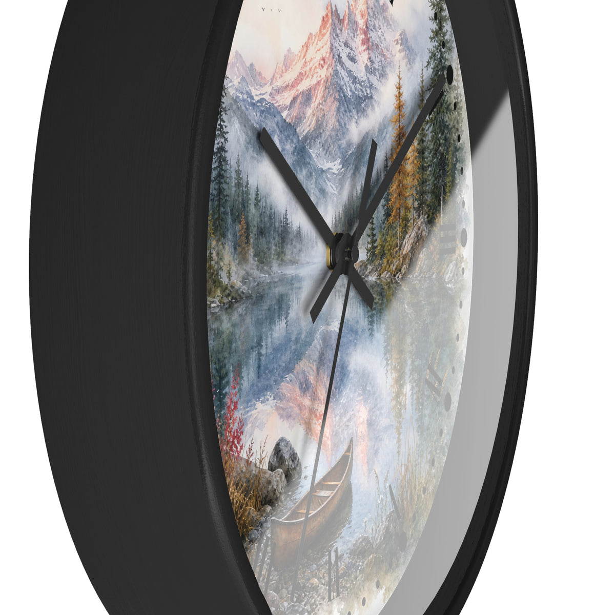 A round wall clock with a black frame and a scenic printed dial showing a mountain lake landscape with trees, a canoe, and misty peaks.