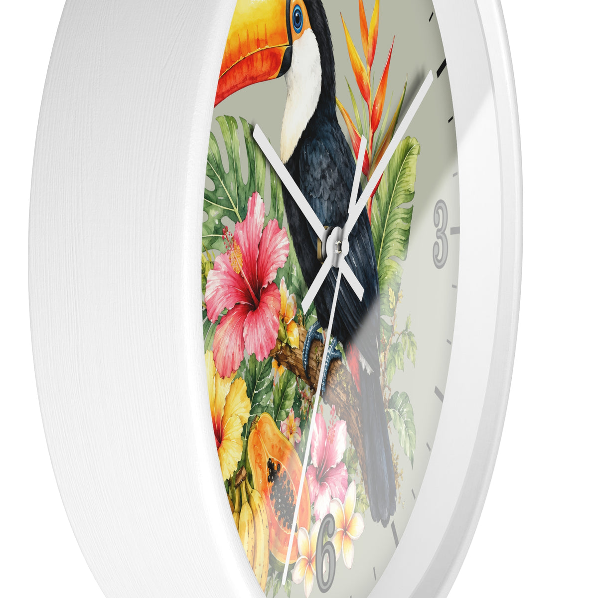 A white round wall clock with a tropical print featuring a toucan, hibiscus flowers, and green leaves on the face, shown against a plain white background.
