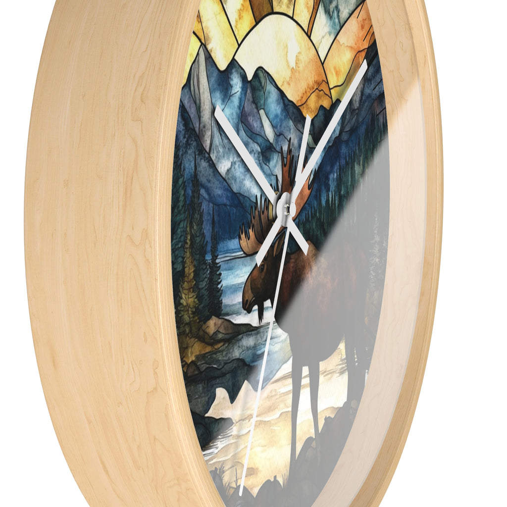 Round wall clock with a light natural wood frame and a stained-glass style print of a moose in a mountain landscape, shown against a white background.
