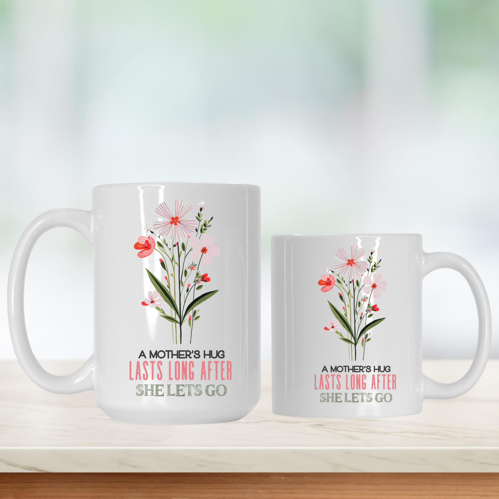15oz and 11oz mugs with floral design and text 'A Mother's Hug Lasts Long After She Lets Go' on a light background 