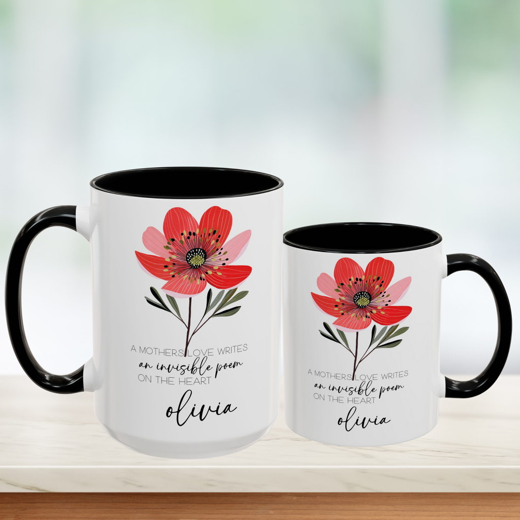 Two white mugs with black handles featuring a red flower design and text on a blurred background.