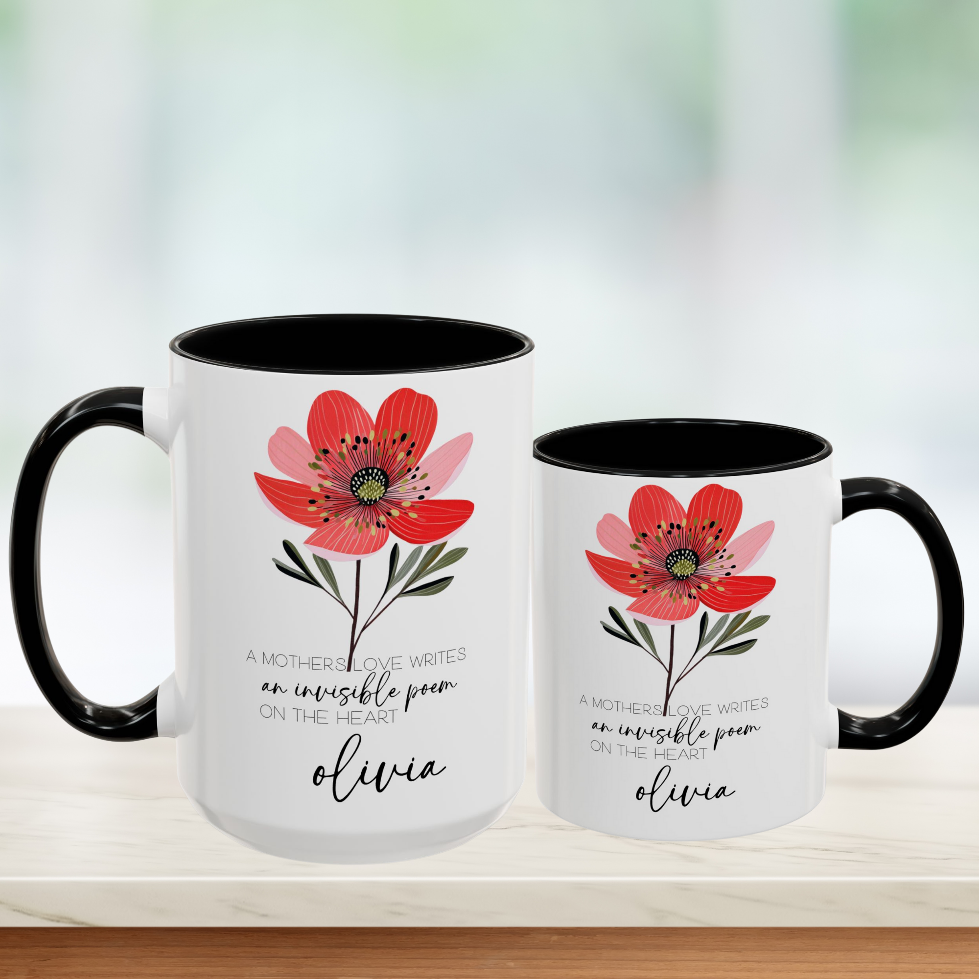 Two white mugs with black handles featuring a red flower design and text on a blurred background.