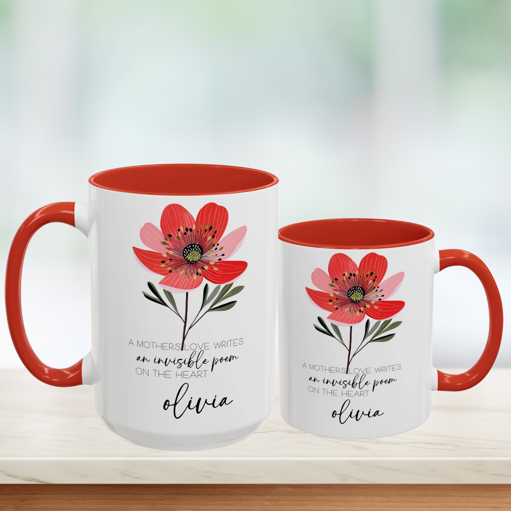 Two white mugs with red interior and handle, featuring a floral design and text on a blurred background.