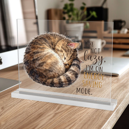 10 inch clear acrylic desk table sign with a hand drawn sleeping tabby cat illustration and text 'I'm not lazy I'm on Energy Saving Mode', sitting on a desk.