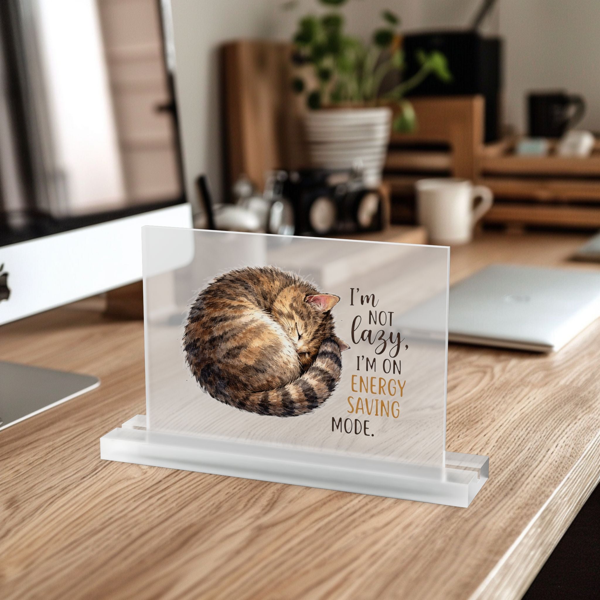 7 inch frosted acrylic table desk plaque with a hand drawn tabby cat and text 'I'm not lazy, I'm on energy saving mode' in a home office setting.