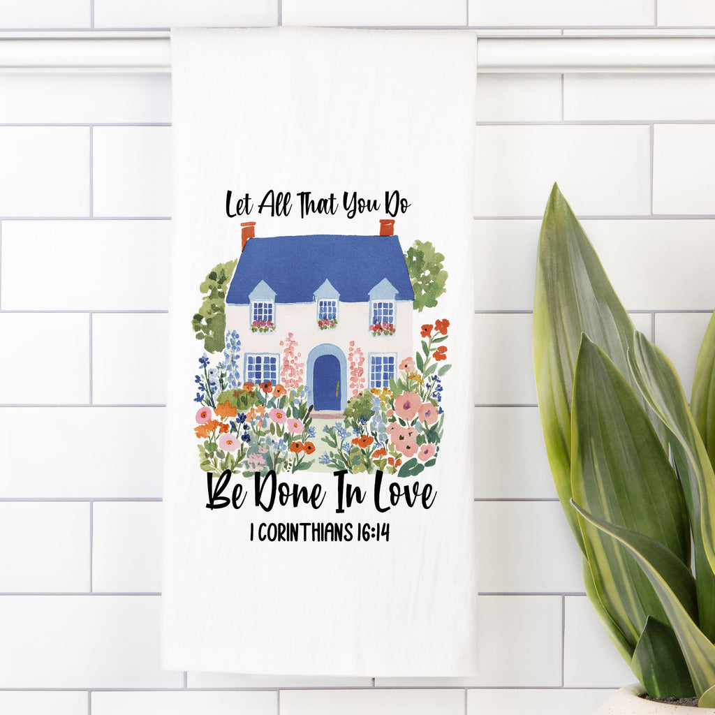 Decorative towel with a house and floral design on a white tiled background