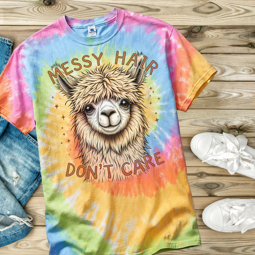Colorful tie-dye t-shirt with a llama graphic and 'Messy Hair Don't Care' text on a wooden surface.
