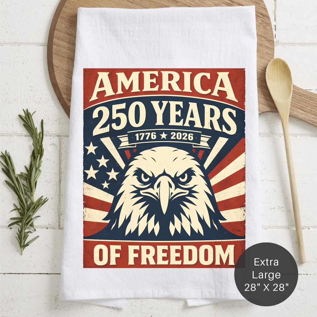 Tea towel with American flag and eagle design celebrating 250 years of freedom, placed on a wooden surface.