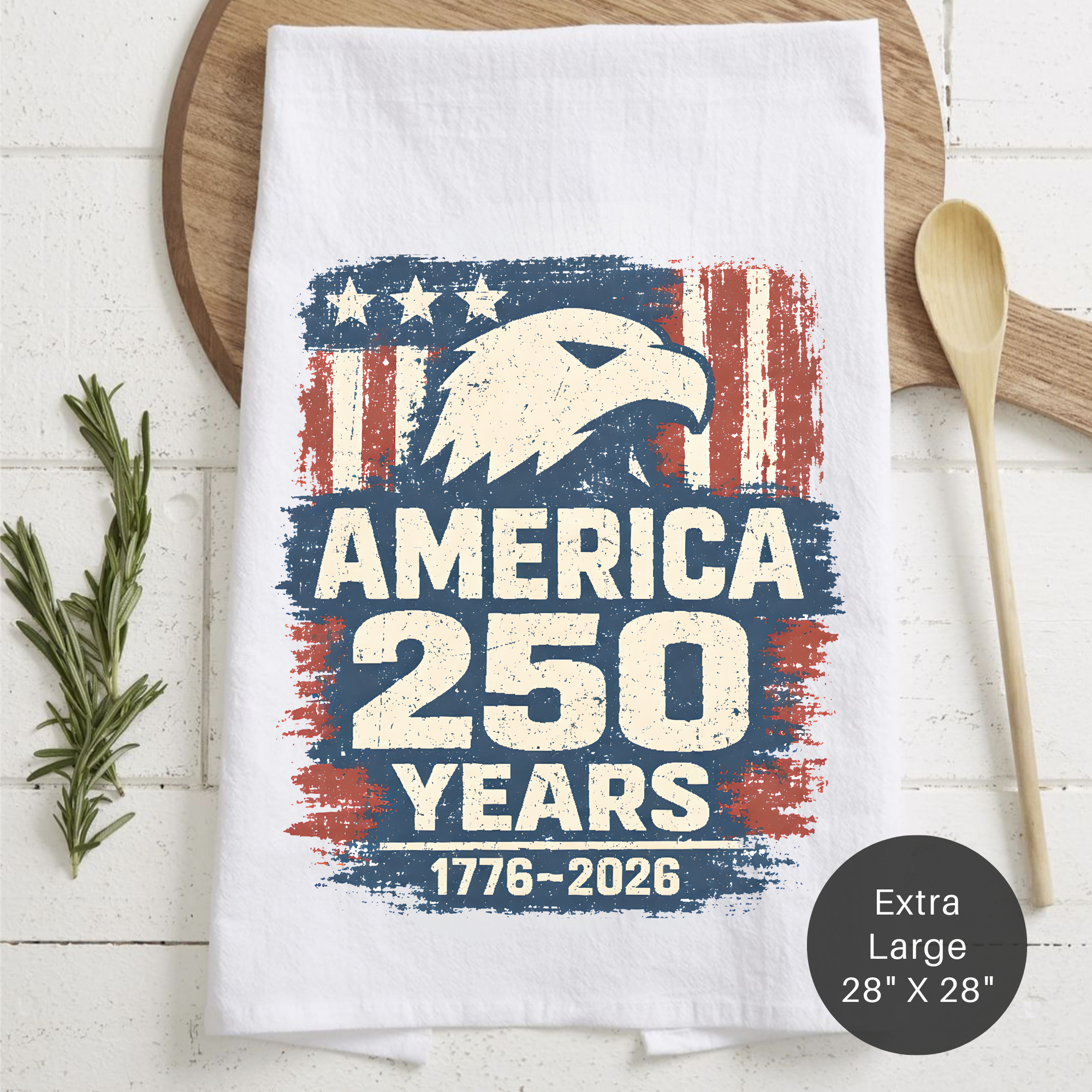 Tea towel with American flag design and eagle, featuring 'America 250 Years' text on a wooden surface.