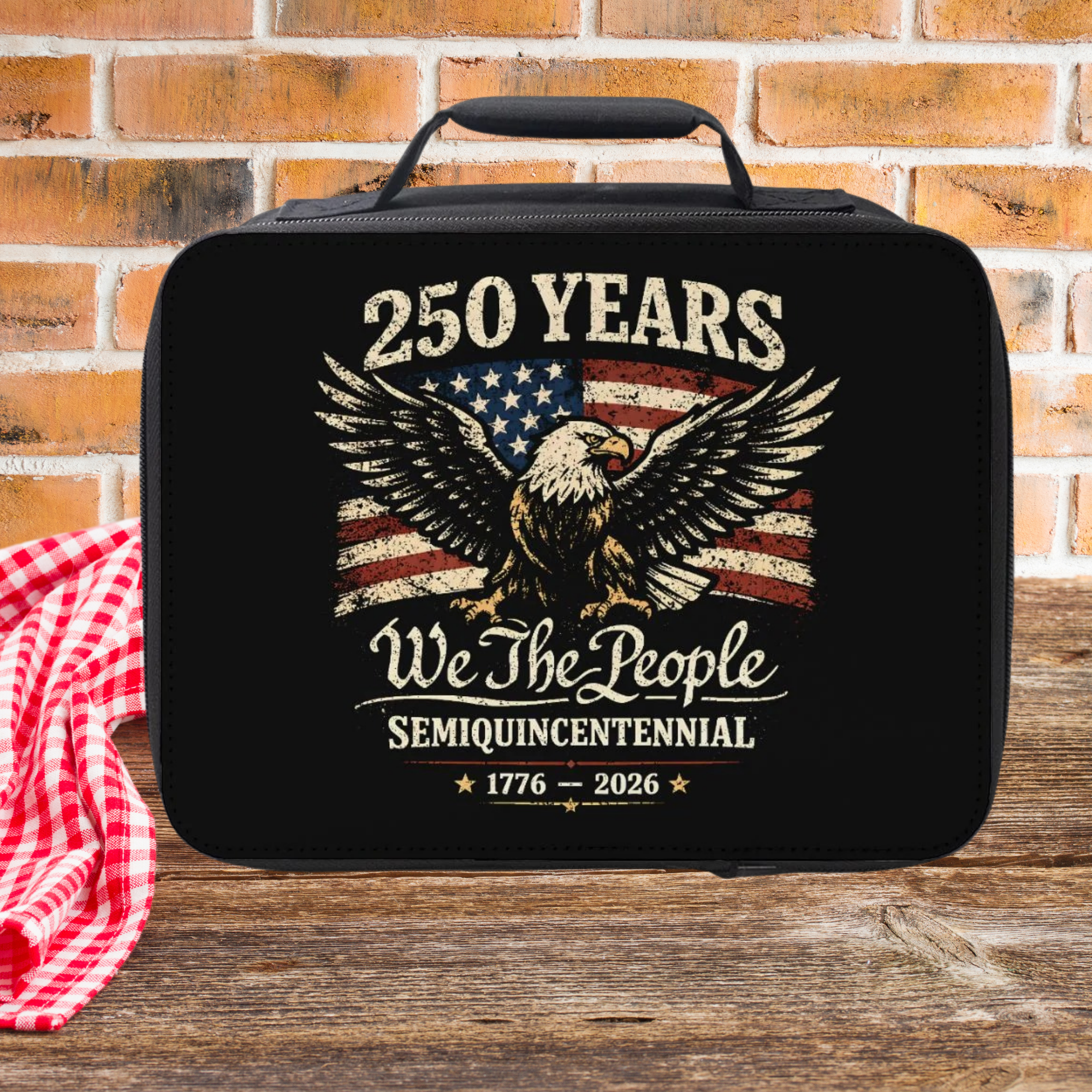 Black bag with American flag and eagle design on a wooden picnic table with brick wall background