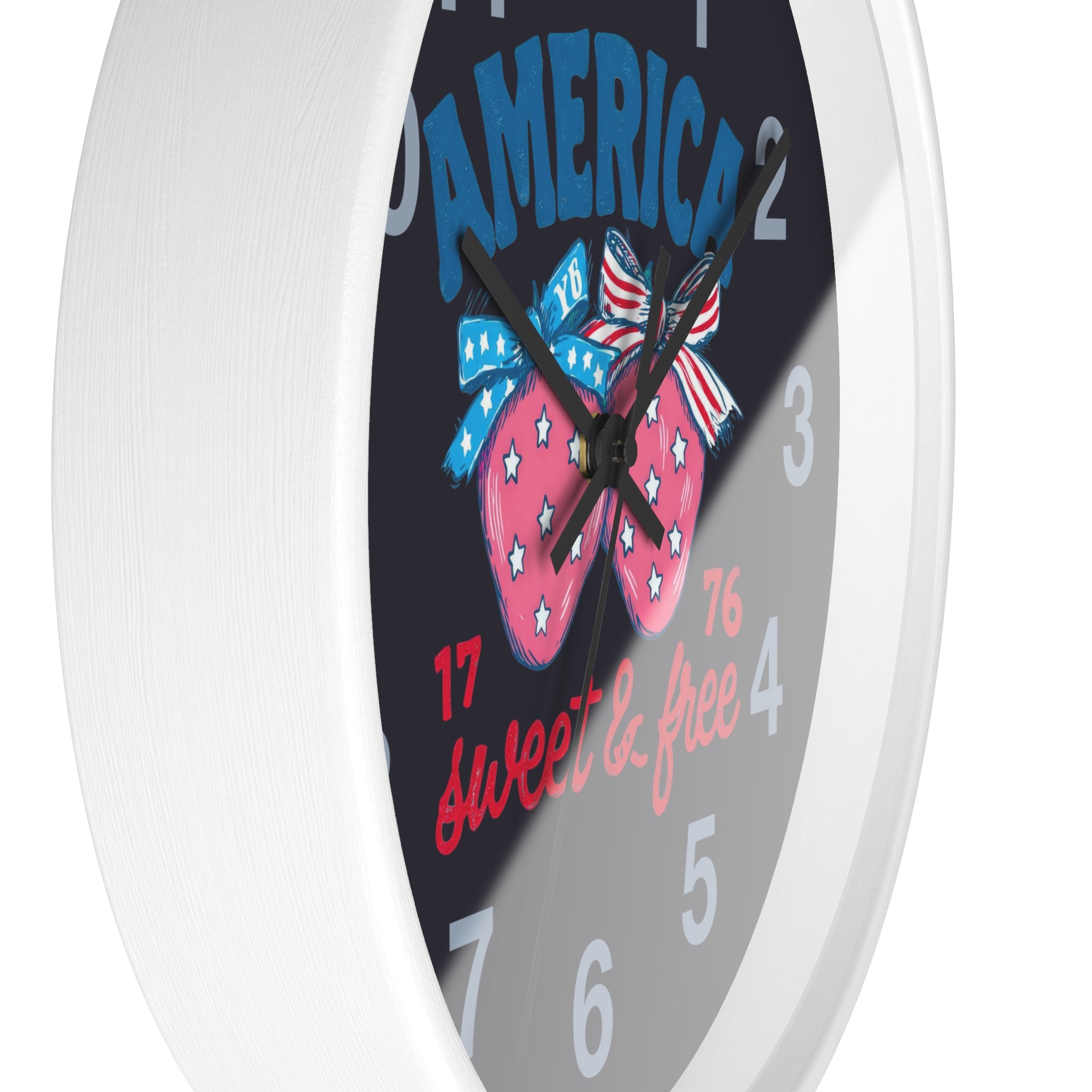 Side view of a round white wall clock with black hands and a design of a strawberry, bow, and text on a black background