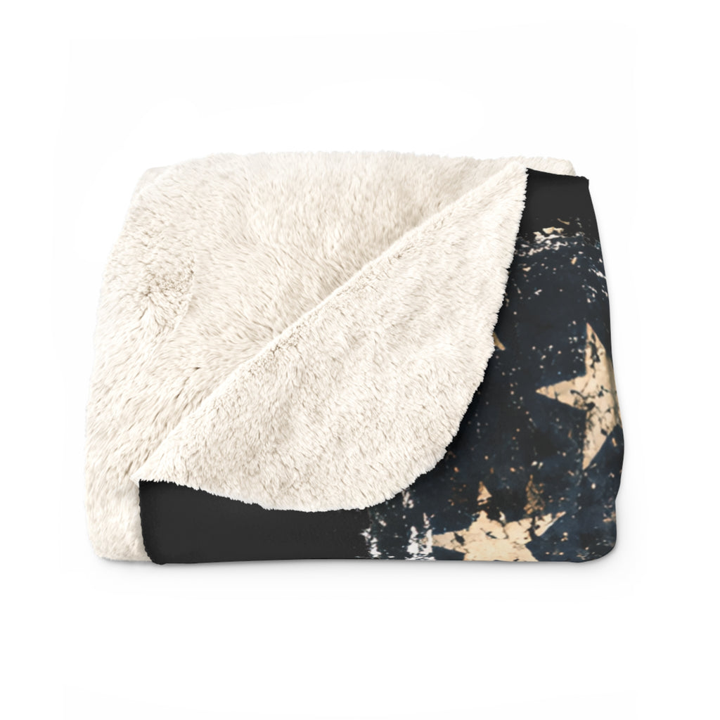 Folded blanket with white sherpa side and black star pattern on a white background