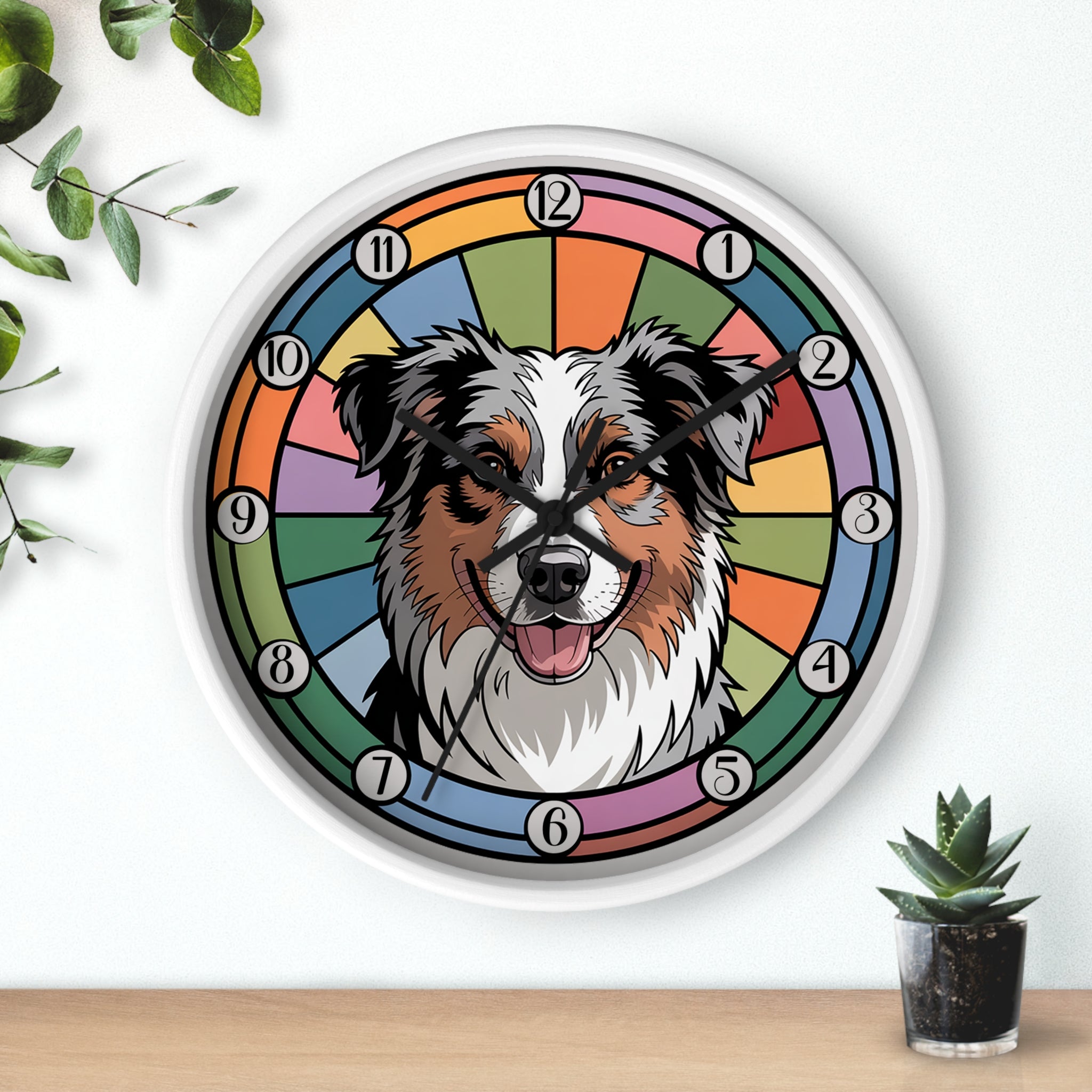 Round white wall clock with a dog's face design on a colorful circular background, placed on a wooden surface with plants.