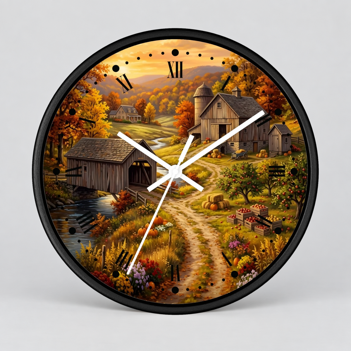 A round wall clock with a black frame and white hands, featuring a colorful autumn farm landscape printed on the face. The artwork shows a dirt path, barns, a covered bridge, a small stream, and fall foliage under a warm sky.
