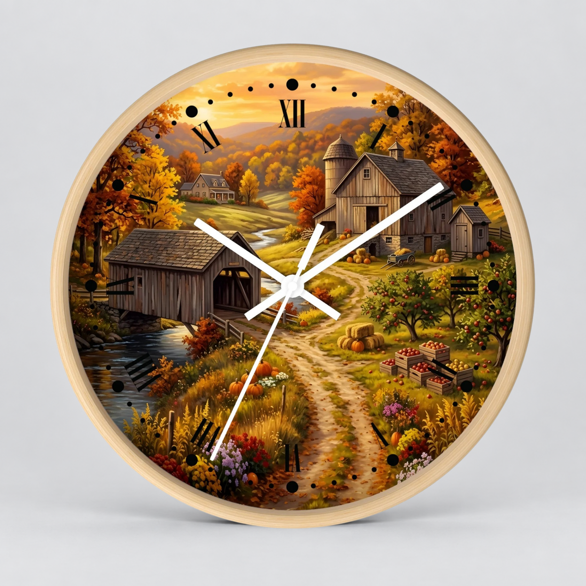 Round wall clock with a light wood frame and a detailed autumn farm landscape printed on the face, featuring barns, a covered bridge, a river, and a dirt path. The clock has black Roman numeral hour markers and white hands against a light gray background.