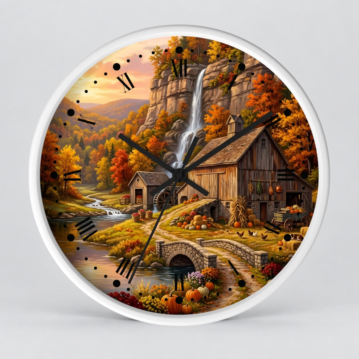 A round wall clock with a white frame and a detailed autumn landscape print featuring a waterfall, rustic barn, stone bridge, pumpkins, and colorful fall foliage. The clock is shown against a light gray background.