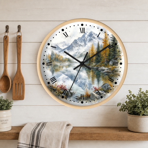 Round wall clock with a scenic mountain lake print, mounted on a white wood plank kitchen wall above a shelf with plants and utensils.