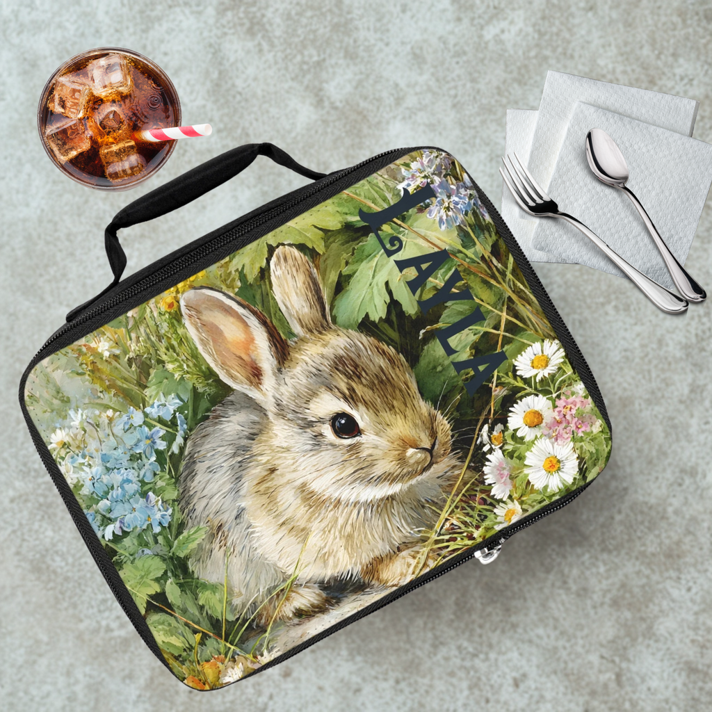 Lunch bag with a rabbit design on a table with a drink and utensils.