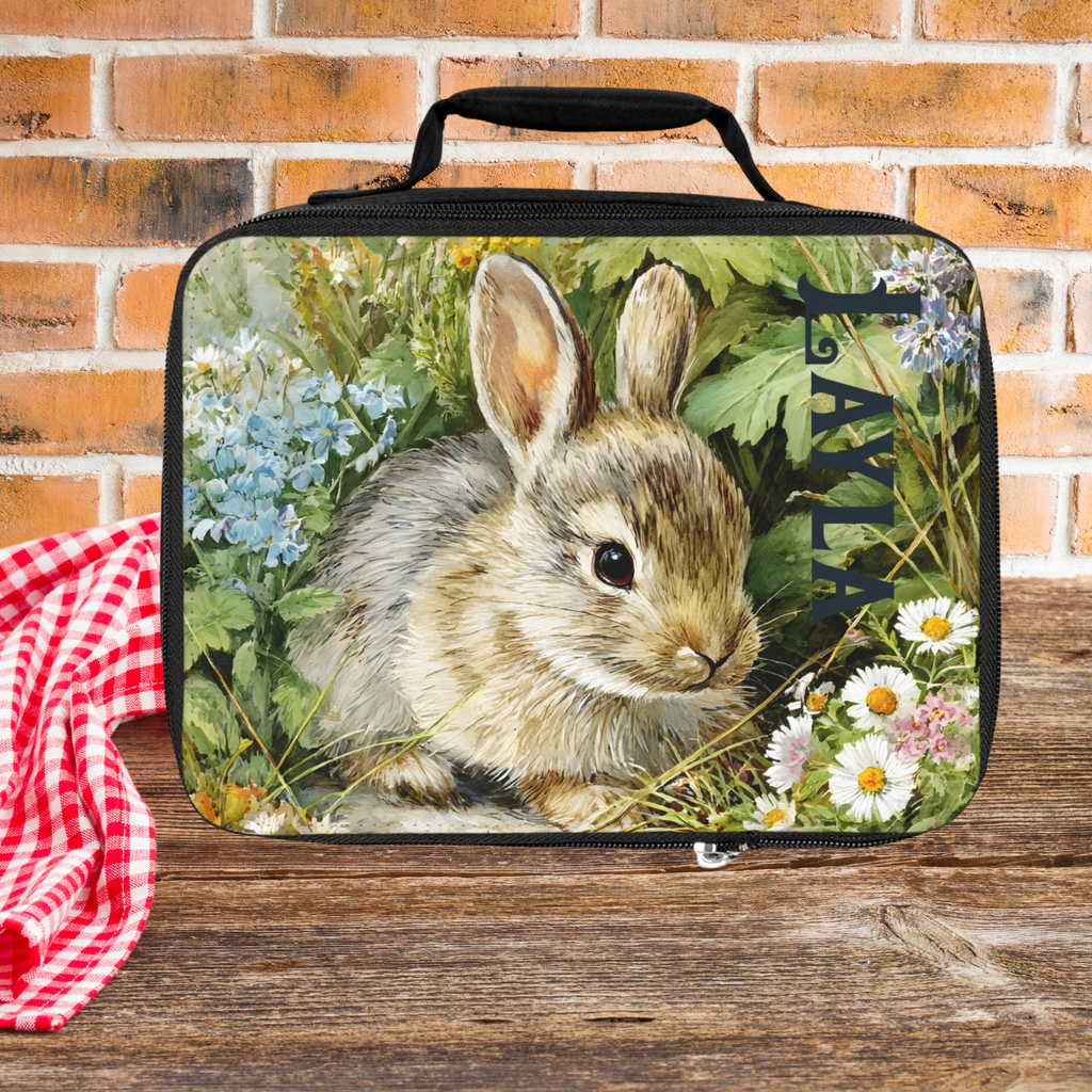 Lunch bag with a rabbit design on a wooden picnic table against a brick wall background