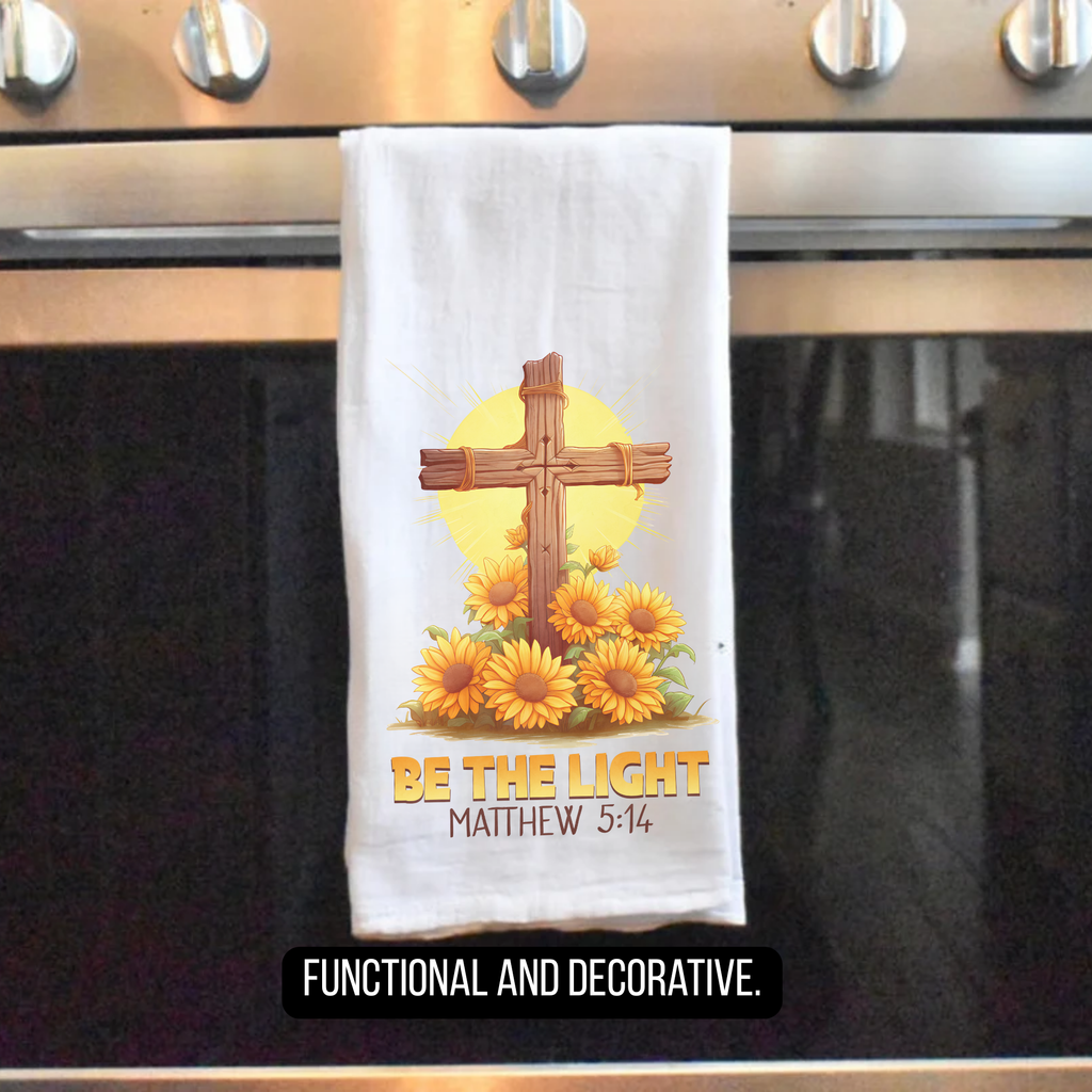 Decorative tea towel with cross and sunflowers hanging on a stove handle.
