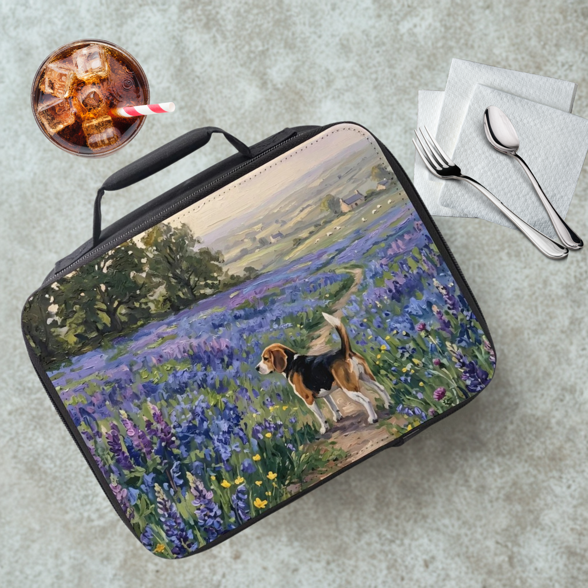 Lunch bag with a painting of a beagle dog in a field of flowers, next to a drink and utensils on a table.