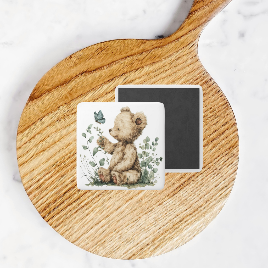 Two square magnets with teddy bear designs on a wooden round tray.