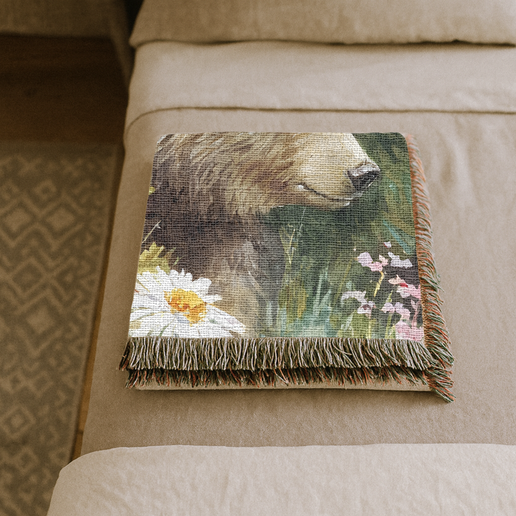 Folded woven blanket with a bear design on a bed.