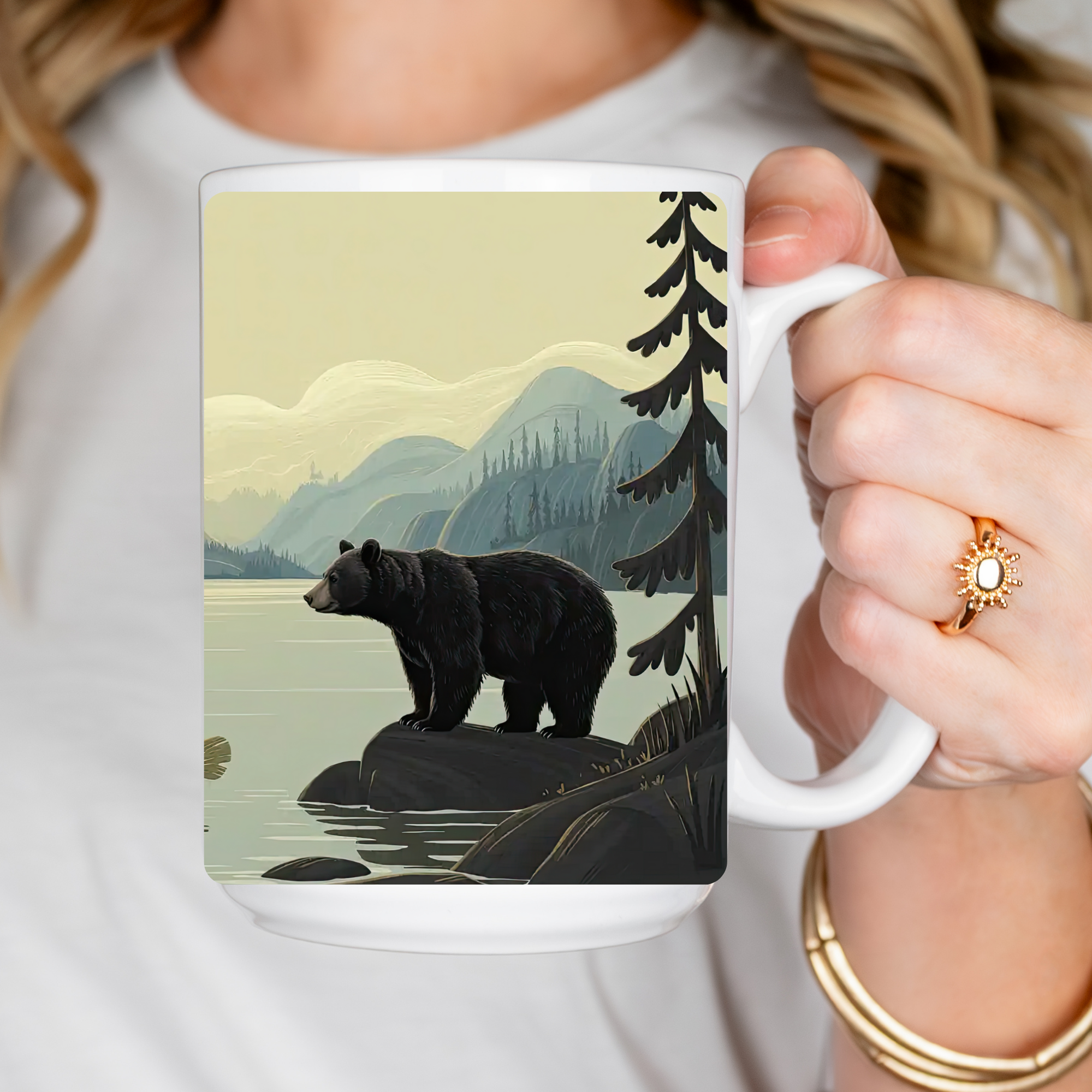 Person holding a mug with a bear and nature design