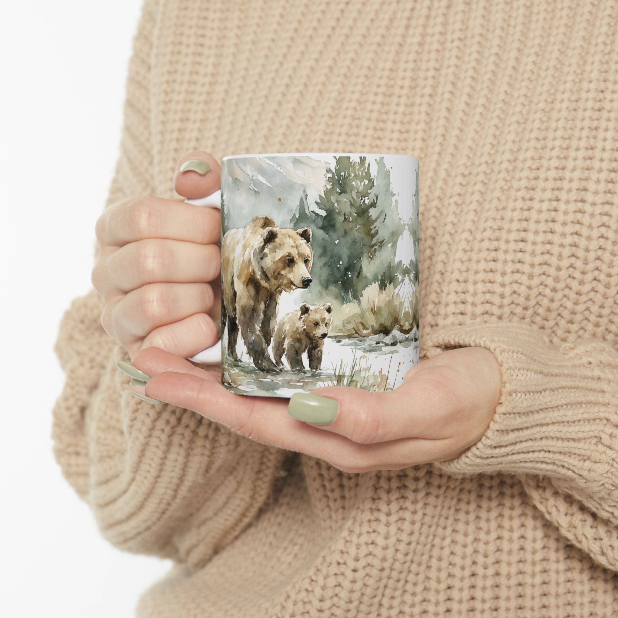 Person holding a mug with a watercolor bear and cub painting design, wearing a beige sweater.
