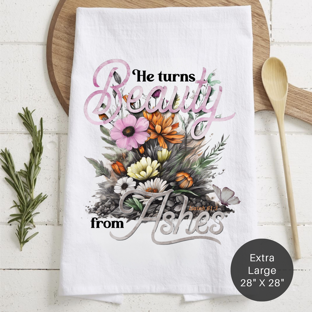 Floral tea towel with text 'He Turns Beauty From Ashes, Isaiah 61:3' on a wooden surface
