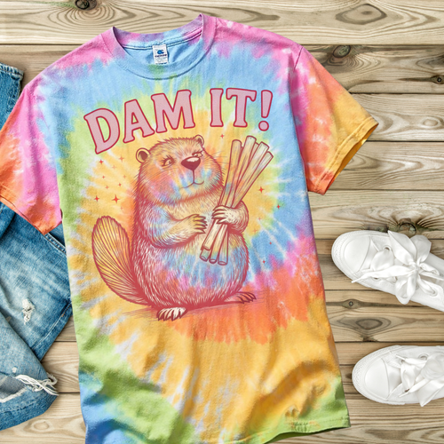 Colorful tie-dye t-shirt with a beaver graphic and 'Dam It!' text on a wooden surface.