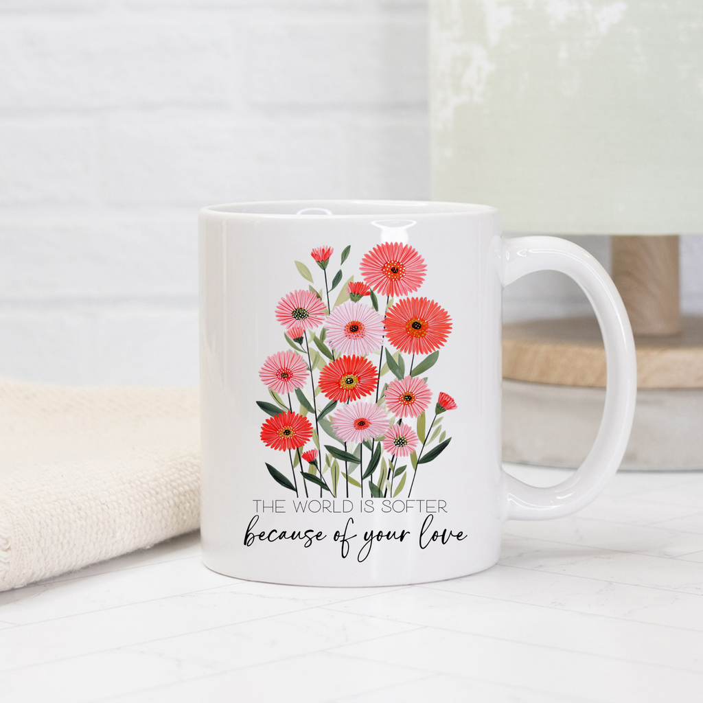 White 11oz mug with floral design and text 'The world is softer because of your love' on a light background