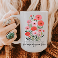 Person holding a 15oz mug with floral design and text 'The world is softer because of your love'
