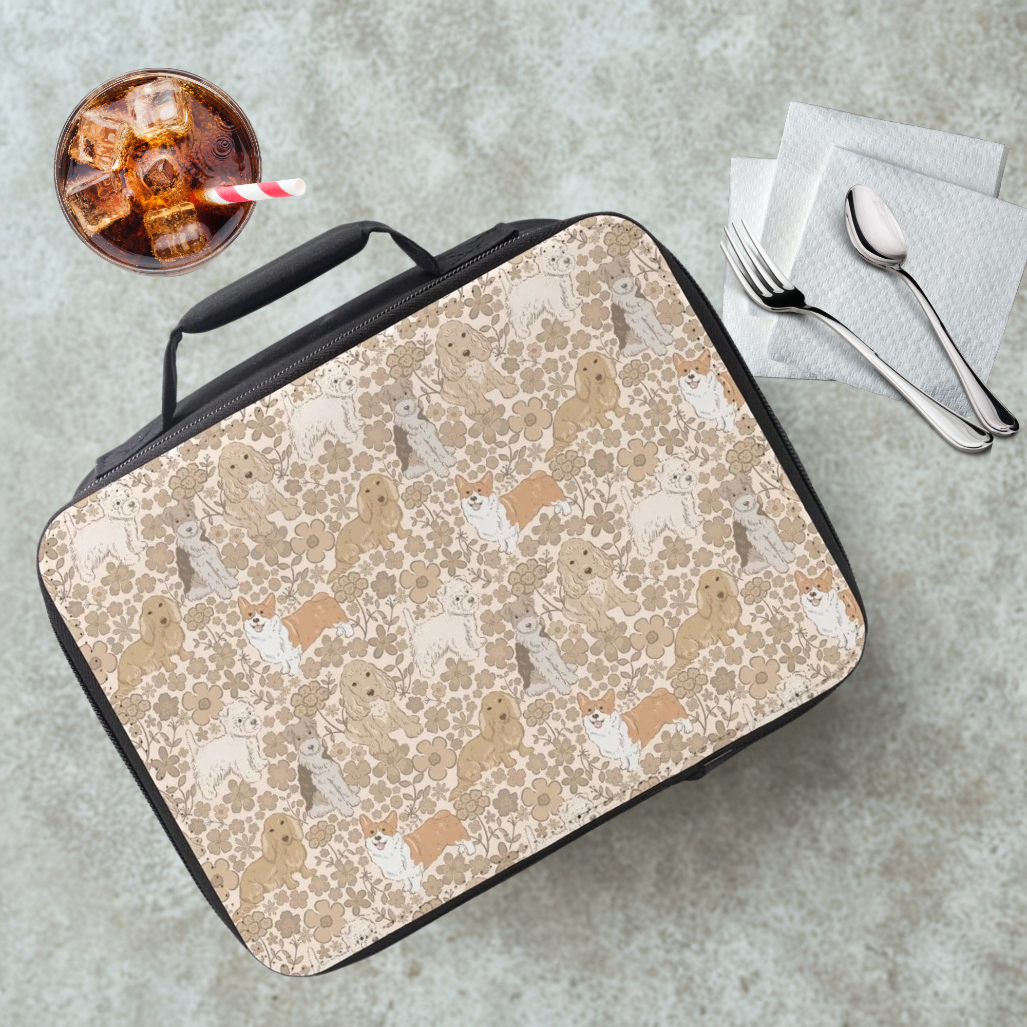 Floral dog patterned lunch bag on a cafeteria table with a drink and utensils 