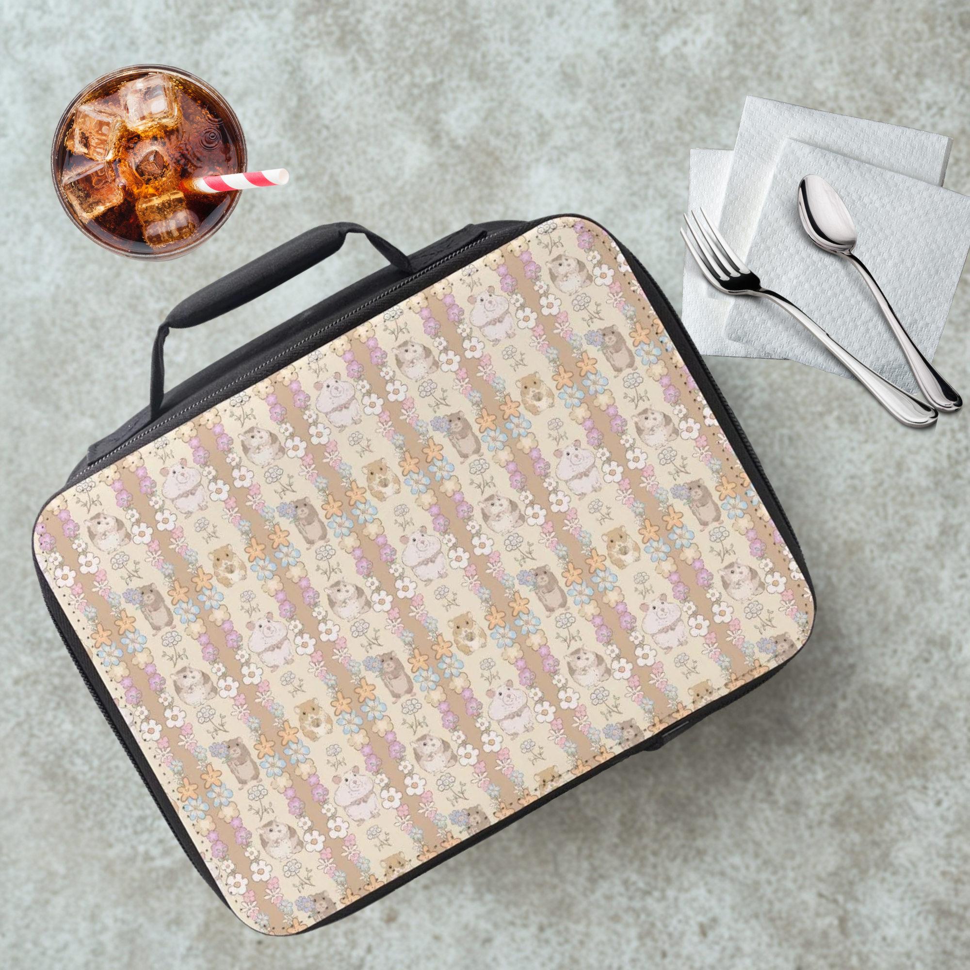 Lunch bag with hand drawn hamsters holding bouquets of flowers in a striped pattern on a cafeteria table with a drink and utensils.