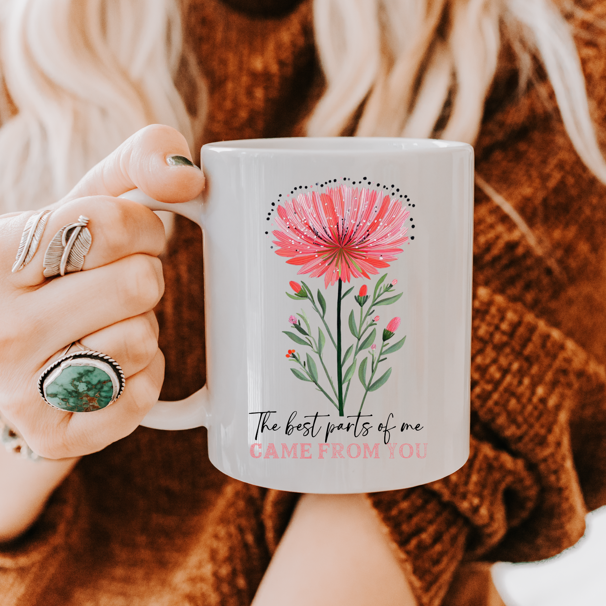 Person holding an 11oz mug with a hand drawn floral design and text 'The best parts of me Came From You'