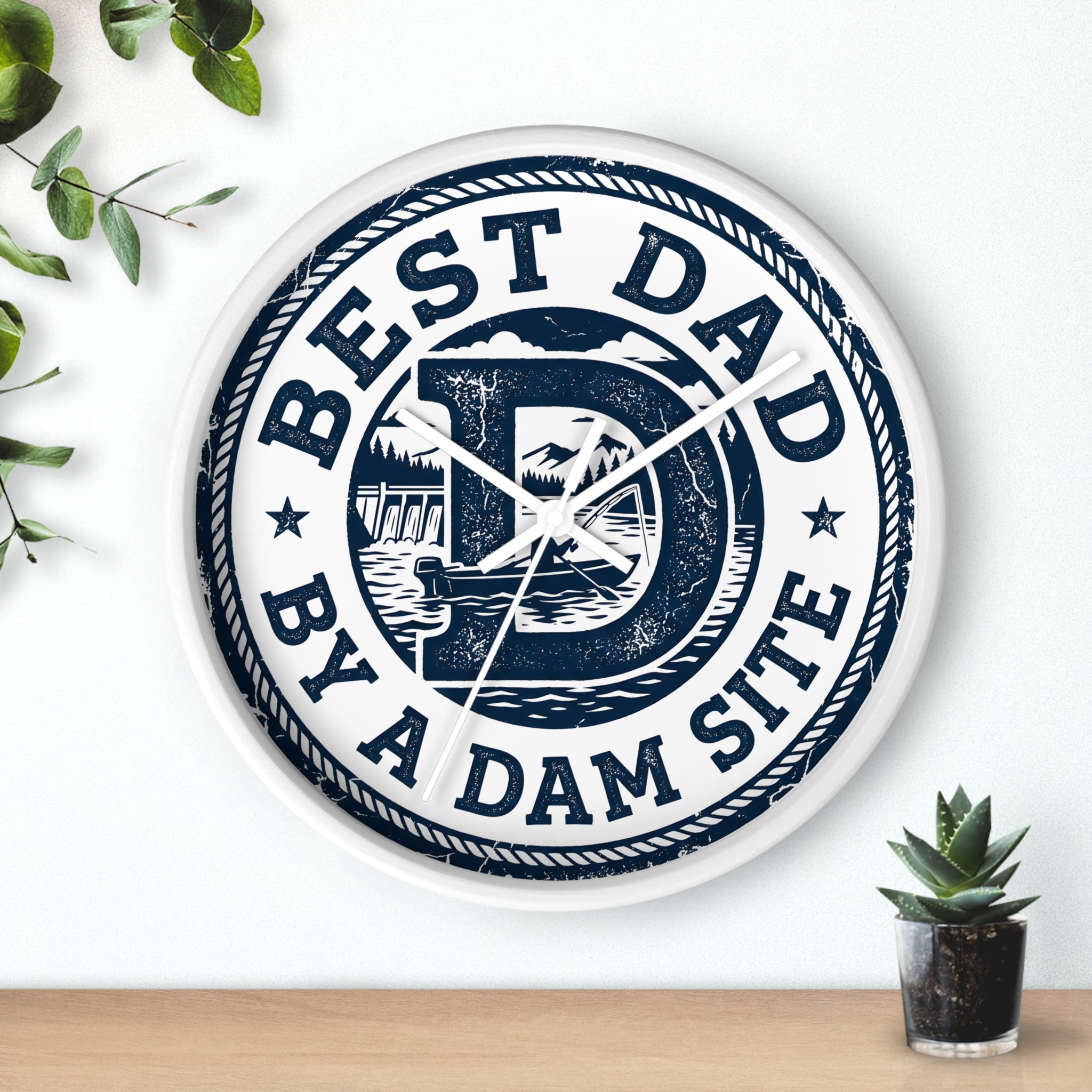 Decorative white wall clock with 'Best Dad by a Dam Site' text on a white wall.